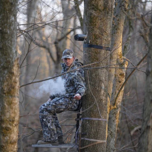 A Hunter Sitting On A Tree With A Scent ElimiDynamically created pagetion Device Installed On A Tree.