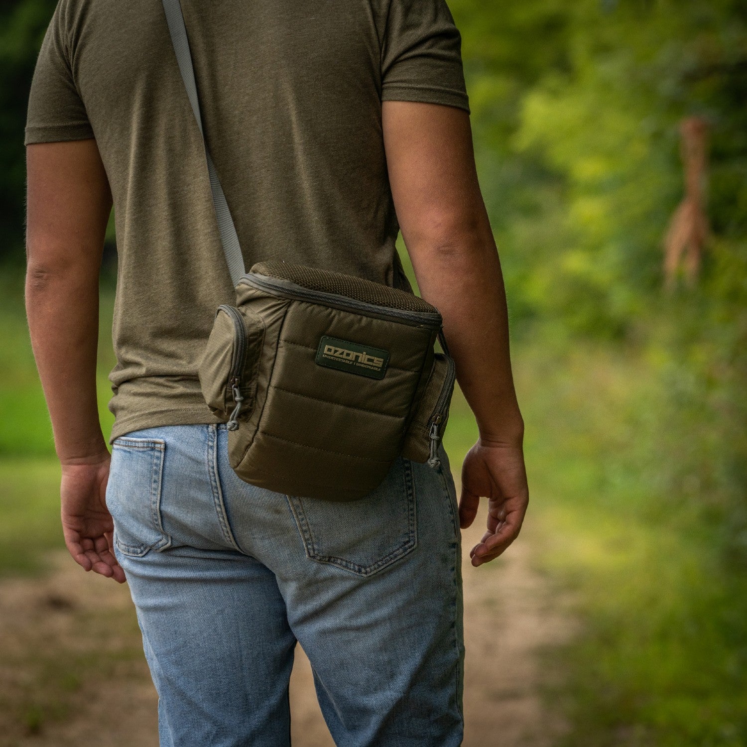 A Man Holding The Bag On His Shoulder On A Dirt Road.